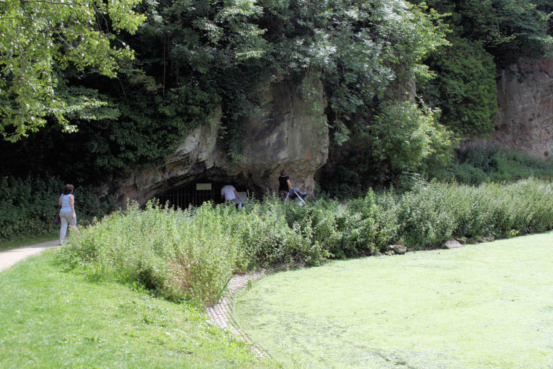 View of a cave (behind a grille) in the steep rocky sides of the gorge. The lake is in the right-hand foreground.